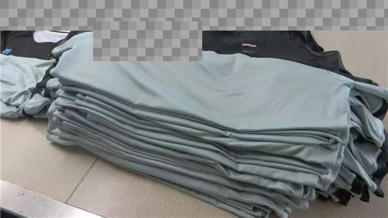A stack of folded two-tone tops with customer identifiers obscured.
