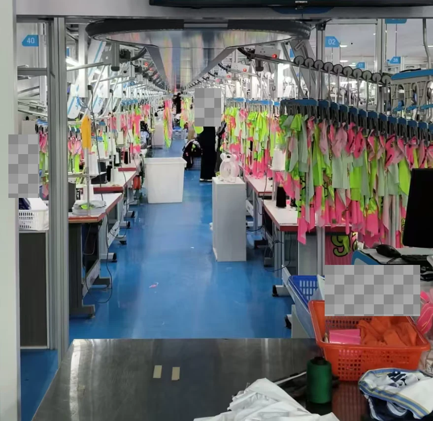 Garments suspended above sewing stations along a production line.